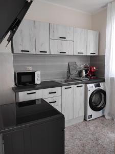 a kitchen with white cabinets and a sink and a microwave at Guest House Dani in Pomorie