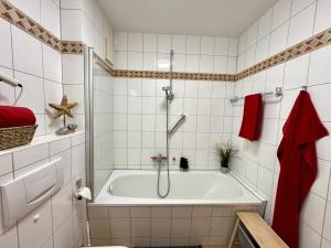 a bathroom with a bath tub with a shower at Oewern Diek App 03 in Wustrow +19 photos