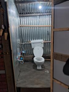 a bathroom with a toilet in a corrugated metal wall at TIS Zipline Campingsite in Gurais