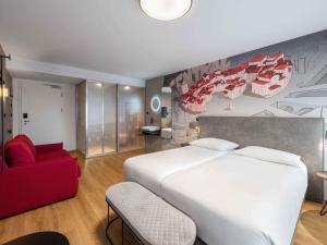 a bedroom with a large white bed and a red chair at ibis Styles Ljubljana Centre in Ljubljana