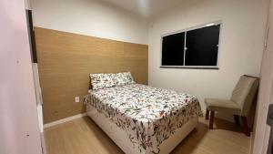 a small bedroom with a bed and a chair at Aprt com ar varada conjugada,piscina in Aracaju