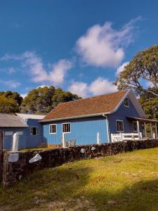 a blue house with a stone wall at Chácara Leopoldo Bairro in Lages