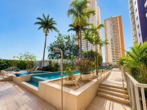 a swimming pool with palm trees and a resort at Luxurious 2-Bedroom Duplex with Gourmet Balcony in Goiânia