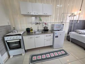 a small kitchen with a sink and a microwave at Espaço Container Itapema - Loft I in Itapema