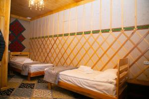 a room with two beds in a room with a wall at Ethno Naryn Guest House in Naryn