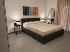 a bedroom with a bed with two tables and a mirror at Moon Apartments B in Soverato Marina