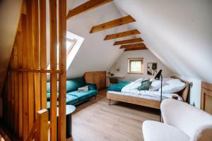 a attic bedroom with a bed and a couch at Domek nad jeziorem z jacuzzi ROMANTICA in Wilamowo
