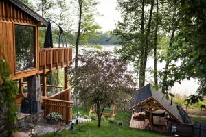 a house with a deck and a lake in the background at Domek nad jeziorem z jacuzzi ROMANTICA in Wilamowo