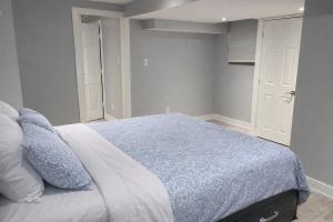 a bedroom with a bed with a blue blanket and pillows at Cozy & Spacious 2-Bedroom Basement Suite in Brampton