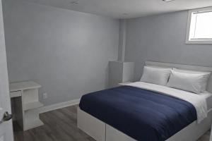 a white bedroom with a bed and a desk at Cozy & Spacious 2-Bedroom Basement Suite in Brampton