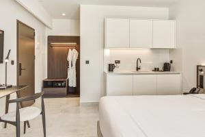 a bedroom with a white bed and a kitchen at Scala Boutique Hotel & Suites - Adults Only in Agia Pelagia