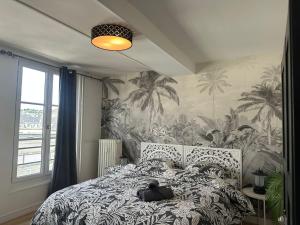 a person laying on a bed in a bedroom with palm wallpaper at Séjour agréable à Plaisir - 456 in Rouen