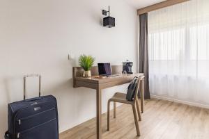 a room with a desk with a suitcase and a computer at Appart'City Confort Mulhouse in Mulhouse