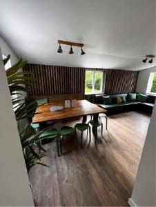 a living room with a wooden table and green chairs at Big Lodge in Peebles