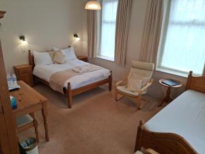 a bedroom with a bed and a chair and two windows at The Reading Rooms in Haydon Bridge