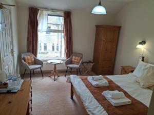 a bedroom with a bed and two chairs and a window at The Reading Rooms in Haydon Bridge