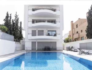 a building with a swimming pool in front of a building at Voula Pool & Sea View & Beach home B1 in Athens