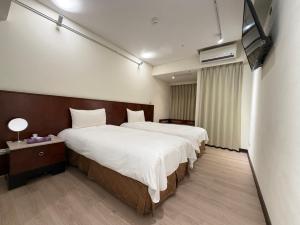 a hotel room with two beds and a television at In One City Inn in Taichung