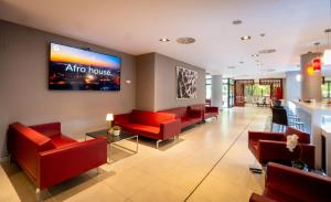 a waiting room with red chairs and a flat screen tv at Turia Granada in Granada