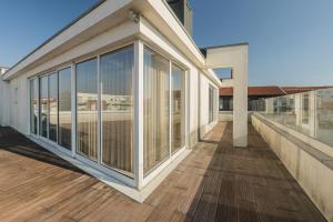 a building with glass doors on a wooden deck at Cantinho do Cávado in Fão