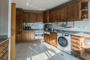a kitchen with wooden cabinets and a washer and dryer at Cantinho do Cávado in Fão