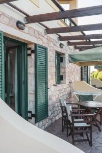 a patio with green shutters and tables and chairs at Angela's studios in Elafonisos