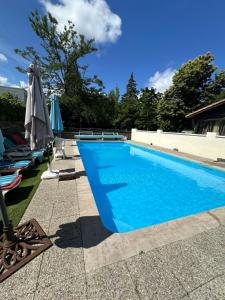a blue swimming pool with chairs and umbrellas at Aux Châtaigniers in Langon