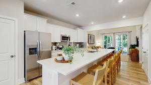 a kitchen with white cabinets and a large island with chairs at Milos Haven house with community pool in Frankford