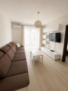 a living room with a brown couch and a tv at Apartmán Hollého in Žilina