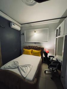 a bedroom with a bed with yellow pillows and a chair at Mak house in Douala