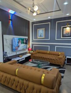 a living room with brown leather furniture and a flat screen tv at Mak house in Douala