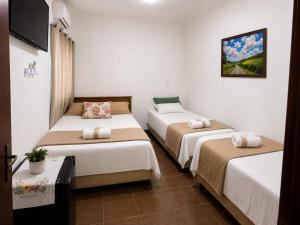 a room with three beds and a flat screen tv at Pousada Yeshua in Paracatu