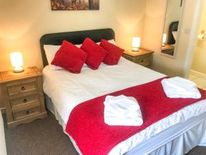a bedroom with a large bed with red pillows at Brewery Lodge Sleeps 4 in Lydney