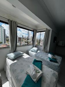 two beds in a room with two windows at Lax Hotel - Acesso através de escadas - 4 andares - Sem elevador in Campina Grande
