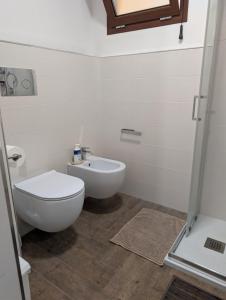 a white bathroom with a toilet and a sink at Koras 142 in Sennori +15 photos