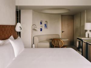 a bedroom with a white bed and a couch at Mondrian Beach Lifestyle Resort By Accor in Cala Llonga