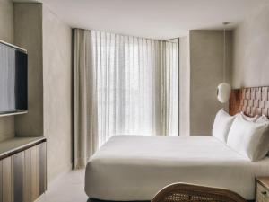 a hotel room with a bed and a large window at Mondrian Beach Lifestyle Resort By Accor in Cala Llonga