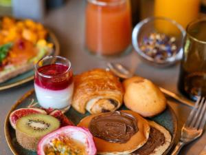 a table with a plate of food with pastries and fruit at Pullman Lyon in Lyon