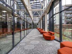 an empty corridor with orange chairs in a building at Mercure Palanga Vanagupe Resort & SPA in Palanga
