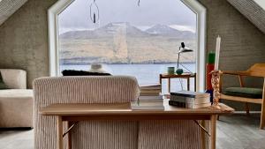 a living room with a table with books and a window at Beitisstova - Mesmerizing Sea & Mountain Views in Stykkið