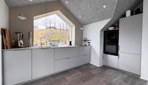 a kitchen with white cabinets and a window at Beitisstova - Mesmerizing Sea & Mountain Views in Stykkið