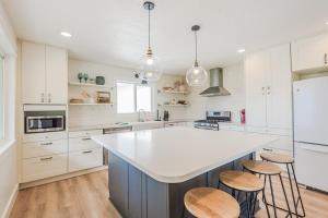 a kitchen with white cabinets and a large island with stools at 72 S Orem Entire Home in Orem