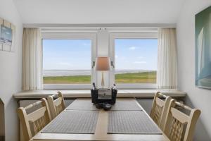 a dining room with a table and chairs and windows at Wattkieker-Stedum in Rantum