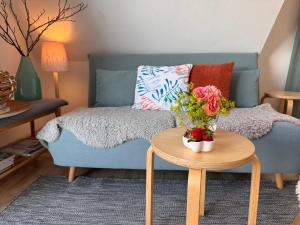 a living room with a blue couch and a table with flowers at Nordlicht, 1-Zimmer mit Meerblickbalkon 500 m zum Strand in Westerholz