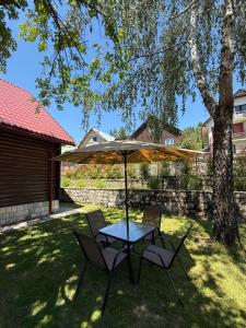 a table and chairs under an umbrella in a yard at Vila Rosa Kolasin in Kolašin