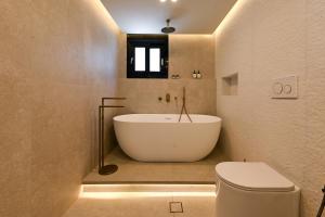 a bathroom with a white tub and a toilet at Ciel Seafront Suites - Lefkada in Lygia