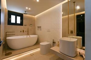 a bathroom with a large white tub and a toilet at Ciel Seafront Suites - Lefkada in Lygia