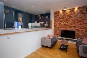 a living room with a brick wall and a tv at Stunning City Centre Duplex in Glasgow
