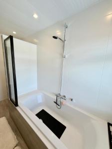 a white bath tub with a shower in a bathroom at Maison Bo Luxury Stay in Historic Lemmer in Lemmer +34 photos