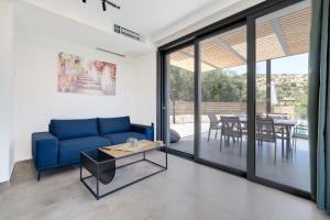 a living room with a blue couch and a table at Villa Ilianthi in Kalamitsi